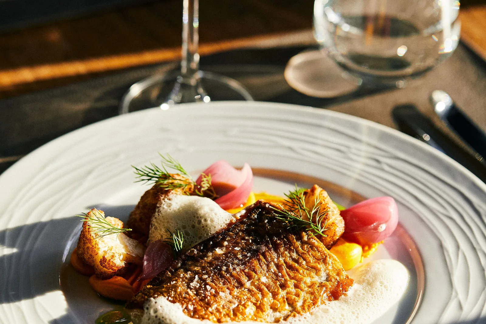 Stekt fisk med sås och grönsaker på tallrik