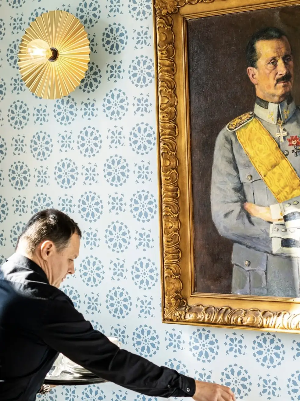 Tarjoilija kattaa pöytää Mannerheimin muotokuvan alla